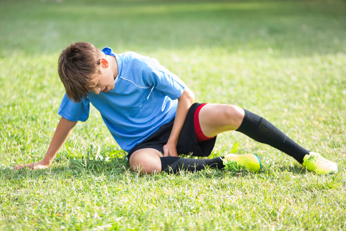 School-aged boy recovering from injury or exertion on athletic field.