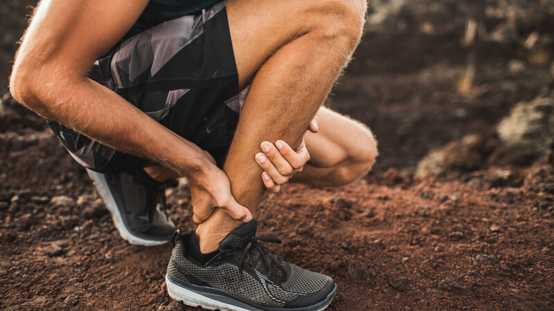 Athlete holding onto their injured Achilles tendon.