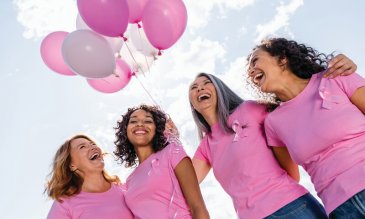 Group of women in pink, with pink balloons in the background. 