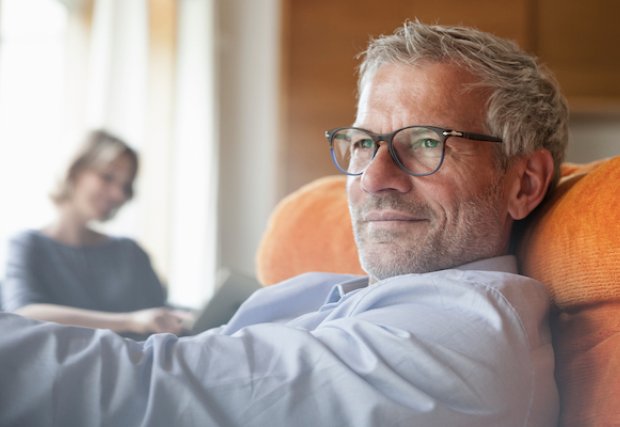 An older man sitting in a chair, looking pensive