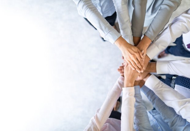 a group of people with their hands in the center of a huddle, a sign of agreement.