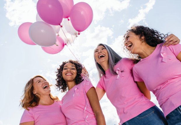 Group of women in pink, with pink balloons in the background. 