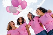 Group of women in pink, with pink balloons in the background. 